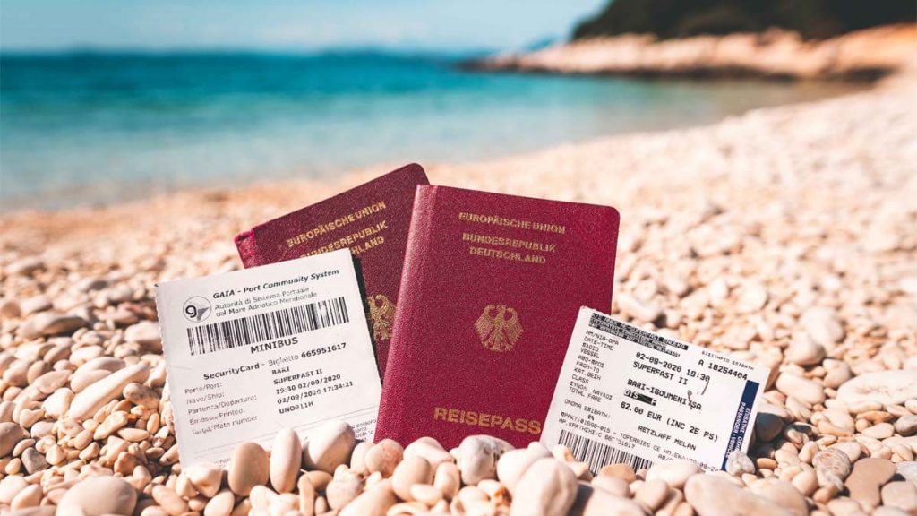 Reisepass mit Fährtickets am Strand für die Einreise nach Griechenland